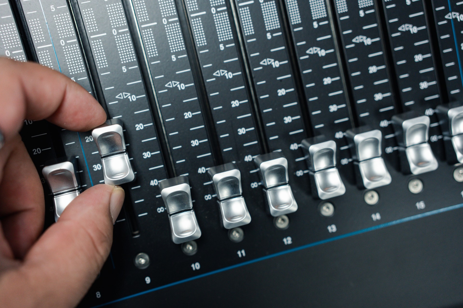 Human hand adjusting buttons on audio mixer.